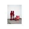 Figurines rouges en bois et bougie décorative sur une surface claire et texturée. Figurines rouges en bois et bougie décorative sur une surface claire et texturée.