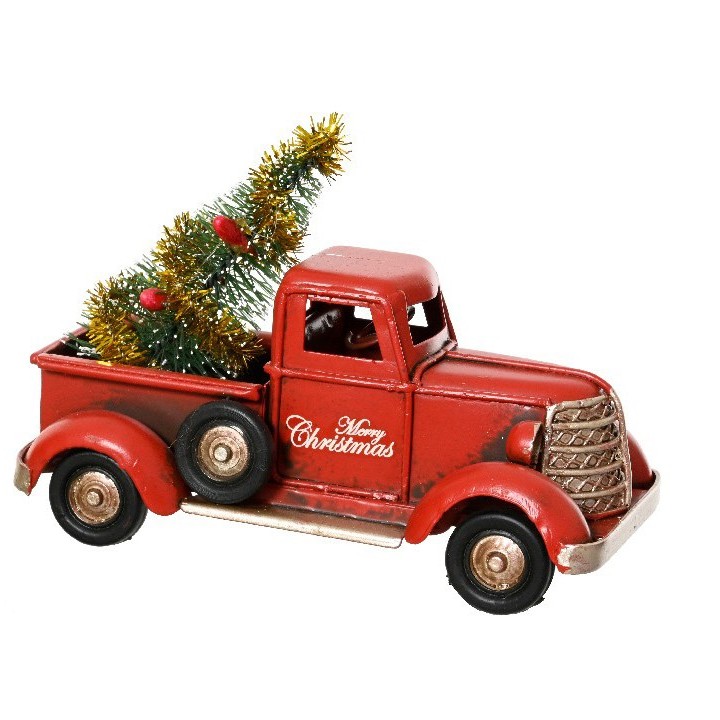 A vintage red truck carries a festive green tree, adorned with gold tinsel and a holiday message.