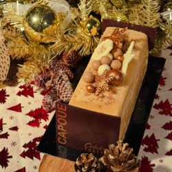 Bûche élégante ornée de décorations dorées et naturelles sur un fond festif.