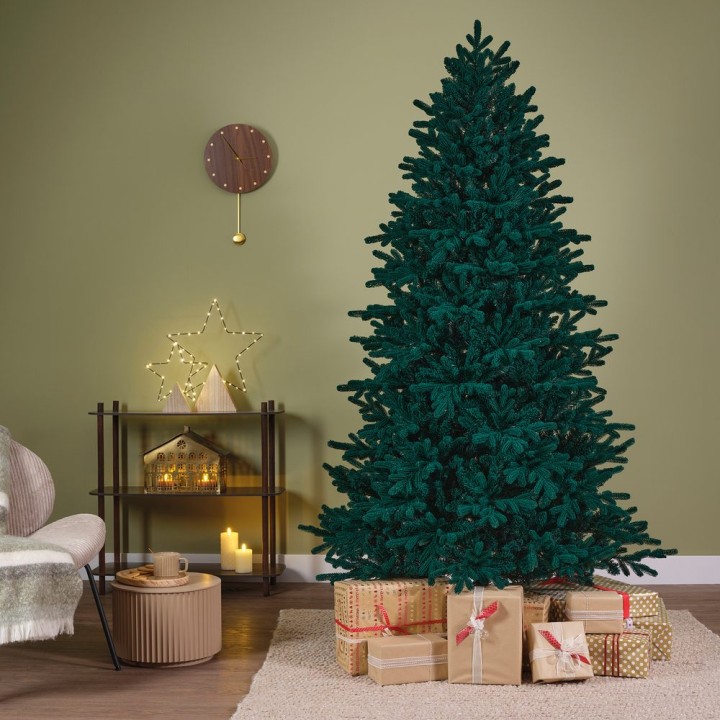 Sapin de Noël vert, décoré, entouré de cadeaux sur un sol en bois clair, mur olive.