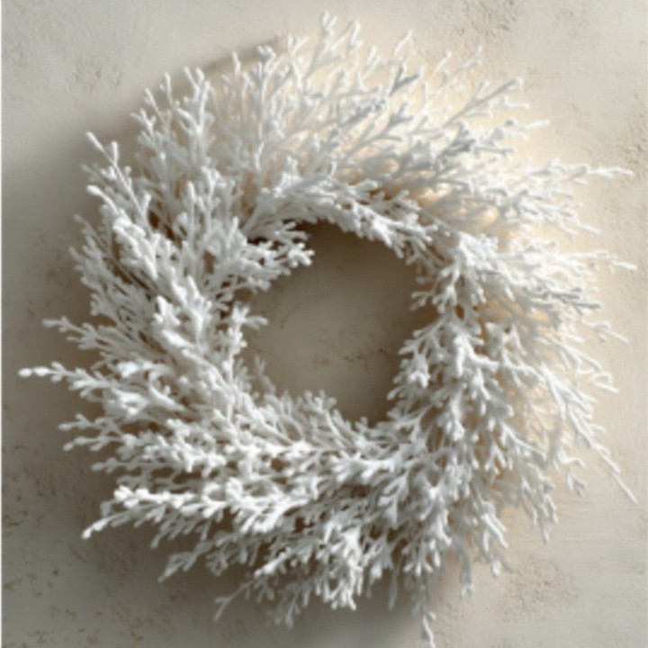 A delicate, white wreath made of branching, coral-like shapes against a soft background.