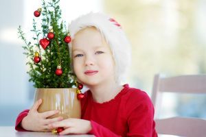 Kind met een levende kerstboom in pot in de armen