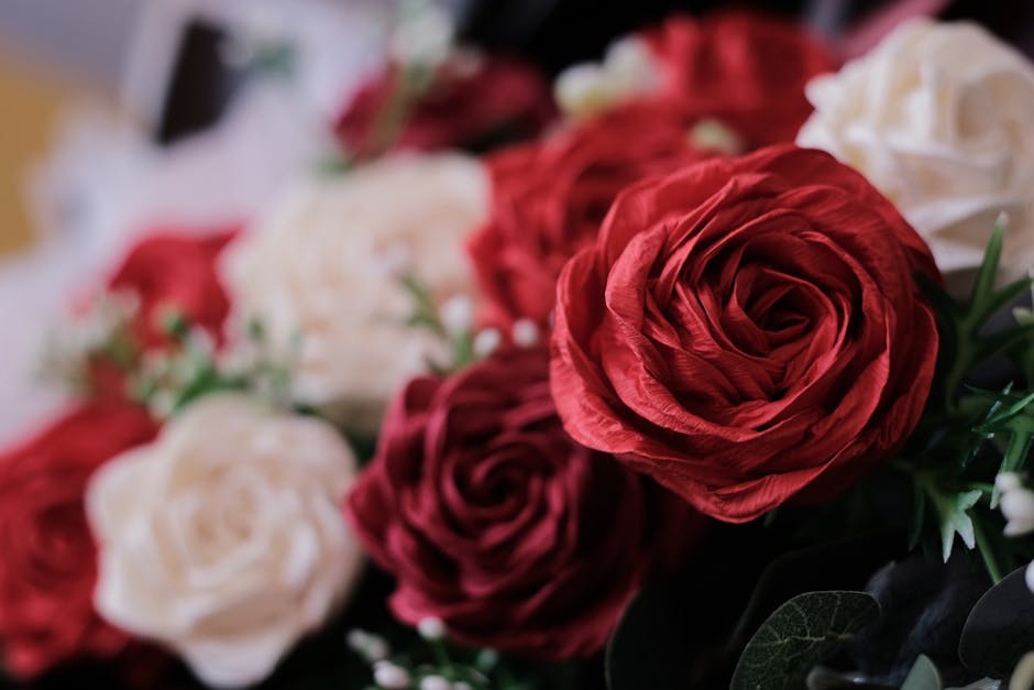 Vue détaillée d'un bouquet magnifiquement organisé de roses rouges et blanches artificielles.